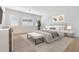 Bright main bedroom with a tufted headboard, white walls, wood floors and large windows with shutters at 17448 W Carlisle Dr, Surprise, AZ 85388