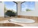 Close up of garden tub with travertine surround and views of desert landscaping at 11070 E Rolling Rock Dr, Scottsdale, AZ 85262