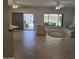 Open-concept living room with neutral tile flooring, ceiling fan, and sliding glass door to backyard at 19595 N Sunburst Way, Surprise, AZ 85374