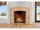 Stone fireplace with fire burning in a living room with wood flooring and natural light at 24724 N 119Th Pl, Scottsdale, AZ 85255