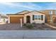 Tan house with brown garage door, dark green shutters, and a landscaped front yard at 40347 W Wade Dr, Maricopa, AZ 85138