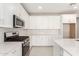 Modern kitchen with white cabinets, stainless steel appliances, and quartz countertops at 40347 W Wade Dr, Maricopa, AZ 85138