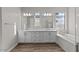 Bright bathroom featuring double sinks, white cabinetry, and a separate tub at 12312 W Luxton Ln, Avondale, AZ 85323