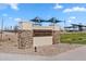 Community entrance sign for Craftsman Park featuring stacked stone, landscaping, and a shaded playground in the background at 37645 W Padilla St, Maricopa, AZ 85138
