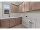 Functional laundry room with built-in cabinets, a sink, and sleek countertops for efficient organization at 32527 N 135Th Dr, Peoria, AZ 85383