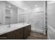 Modern bathroom with dual sinks, a large mirror, a tiled shower, and wood flooring at 24567 W Alta Vista Rd, Buckeye, AZ 85326