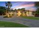 Stunning single-story home with lush landscaping, palm trees, circular driveway, and warm exterior lighting at sunset at 2440 N Maple --, Mesa, AZ 85215