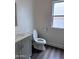 Simple bathroom with gray vanity, toilet and dark wood-look floors at 6245 W Southgate St, Phoenix, AZ 85043