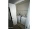 A laundry room with a white washer and dryer set, with shelving above at 23671 W Wayland Dr, Buckeye, AZ 85326