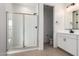 Modern bathroom showcasing a glass-enclosed shower with white tiling, a sleek vanity, and neutral colored tile floors at 40075 W Elm Dr, Maricopa, AZ 85138