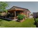 Landscaped backyard with patio, covered pergola, and colorful flowers at 160 S Azteca Dr, Eloy, AZ 85131