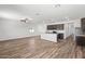 Open living room with wood flooring, large windows, and a view of the kitchen at 680 W Crowned Dove Trl, Casa Grande, AZ 85122