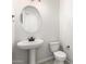 Bright half-bathroom features a pedestal sink, oval mirror, tile flooring, and sleek fixtures at 20262 W Hollyhock St, Buckeye, AZ 85396