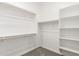 A walk-in closet with white shelves, hanging rods, and soft carpet at 20262 W Hollyhock St, Buckeye, AZ 85396