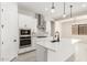 Modern kitchen features white cabinets, stainless steel appliances, an island with sink, and tile backsplash at 20262 W Hollyhock St, Buckeye, AZ 85396