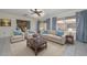 Inviting living room with a ceiling fan, plush furniture, blue accents, and views of the well-maintained backyard at 10802 W Cameo Dr, Sun City, AZ 85351