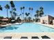 Large community swimming pool surrounded by many palm trees, lounge chairs, and a clear blue sky at 7417 N Via Camello Del Norte -- # 160, Scottsdale, AZ 85258