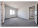 Spacious bedroom with neutral walls and carpet features a bright window and doorway with natural lighting at 1101 E Dolores Rd, Phoenix, AZ 85086