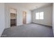 Large bedroom with neutral carpet, closet and bathroom doorways and bright window illuminating the room with natural light at 1101 E Dolores Rd, Phoenix, AZ 85086