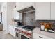 Stylish kitchen with stainless steel range, dark gray backsplash and white cabinets at 1101 E Dolores Rd, Phoenix, AZ 85086