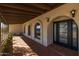 Covered patio with terracotta tile, arched windows, and a modern door at 8320 E Quill St, Mesa, AZ 85207