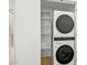 White laundry closet with stacked washer and dryer and open shelves for storage at 7127 E Rancho Vista Dr # 4012, Scottsdale, AZ 85251
