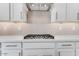 A modern kitchen features white cabinetry and a gas cooktop with a decorative tile backsplash at 17632 W Oregon Ave, Litchfield Park, AZ 85340