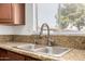 Well-lit kitchen sink with updated faucet, granite countertops, and window overlooking backyard at 3222 W Wagoner Rd, Phoenix, AZ 85053