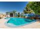 A backyard pool is surrounded by mature trees and landscaping, next to a shed with ocean themed mural at 4020 W Anderson Dr, Glendale, AZ 85308