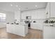 Modern white kitchen with an island, stainless steel appliances, and wood-look tile flooring at 5688 S 243Rd Dr, Buckeye, AZ 85326