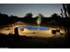 Inviting kidney-shaped pool with lounge chairs and umbrellas at night at 8619 N 192Nd Ave, Waddell, AZ 85355