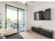 Bedroom with sliding glass doors to balcony, large TV, and a dark colored sofa with throw blanket at 2511 W Queen Creek Rd # 179, Chandler, AZ 85248