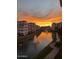 Breathtaking sunset view of the community's waterway featuring lush green landscaping, a fountain, and building exteriors at 2511 W Queen Creek Rd # 179, Chandler, AZ 85248