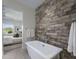 Modern bathroom features a soaking tub with stone accent wall, and bedroom in background at 37200 N Cave Creek Rd # 2110, Scottsdale, AZ 85262