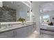 Bright bathroom with stone wall accent, large mirror, and sinks, and bedroom in background at 37200 N Cave Creek Rd # 2110, Scottsdale, AZ 85262