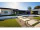 A modern home with lush turf landscaping and a walkway to the stone-clad front entry at 12232 N 65Th Pl, Scottsdale, AZ 85254