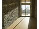 Hallway featuring stone walls, light hardwood floors, and a large glass window at 12232 N 65Th Pl, Scottsdale, AZ 85254