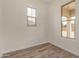 Bright bedroom features wood-look tile flooring, two windows, and neutral paint, creating a welcoming space at 19679 E Estrella Rd, Queen Creek, AZ 85142