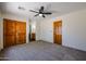 Spacious bedroom with wood doors, ceiling fan, and carpeted floor at 19927 W Meadowbrook Ave, Litchfield Park, AZ 85340