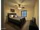 Bedroom with a dark-colored bed set, bench, ceiling fan and a window with natural light at 45737 W Ranch Rd, Maricopa, AZ 85139