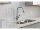 Close-up of a modern kitchen sink with stainless steel fixtures and a stylish white backsplash at 4333 N 59 Th Ave, Phoenix, AZ 85033