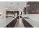 Open-concept kitchen featuring dark wood cabinets, subway tile backsplash, a gas cooktop and stainless steel appliances at 19539 E Estrella Rd, Queen Creek, AZ 85142