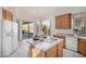 Open kitchen layout with a center island, white appliances, and access to the outdoor patio at 7358 E Red Hawk St, Mesa, AZ 85207