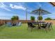 Landscaped backyard with outdoor seating, dining table, and a fire pit, perfect for outdoor gatherings at 40095 W Hensley Way, Maricopa, AZ 85138