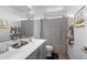 A bathroom with a dual sink vanity, modern fixtures, and geometric shower curtain at 3930 S 58Th Ln, Phoenix, AZ 85043