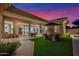 Outdoor living space with covered patio, lush grass, desert landscaping, and evening sky at 13778 E Charter Oak Dr, Scottsdale, AZ 85259