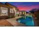 Backyard pool and patio with desert landscape, exterior lighting and a sunset sky at 13778 E Charter Oak Dr, Scottsdale, AZ 85259