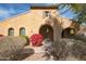 Tan stucco house with arched entryway, red flowers, and mature shrubs at 18206 W Sells Dr, Goodyear, AZ 85395