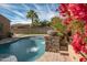 Stunning pool area with a stone water feature and vibrant flowers at 18206 W Sells Dr, Goodyear, AZ 85395