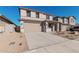 Two-story house with tan exterior, two-car garage, and desert landscaping at 18428 W Poston Dr, Surprise, AZ 85387